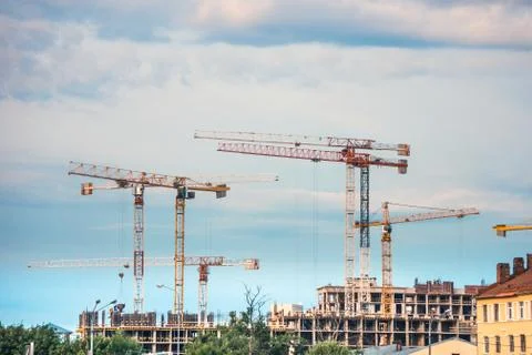 Industrial construction cranes operating on construction site Stock Photos