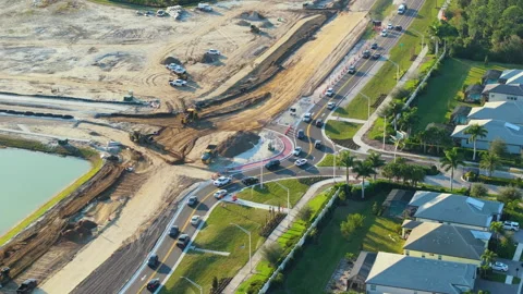 Industrial construction roadworks at roundabout intersection with moving cars in Stock Footage 278512449