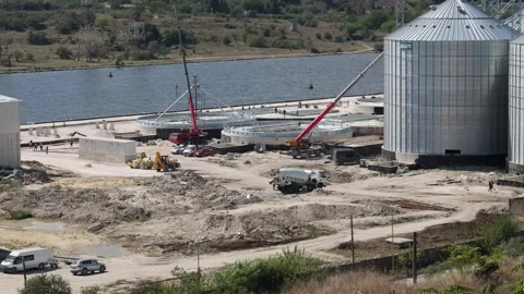 Industrial construction site building grain silos near a river Stock Footage 345928240