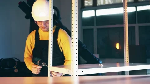 Industrial construction worker assembling shelf rack with a power screwdriver Stock Footage 145687489