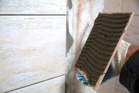 Industrial construction worker installing small ceramic tiles on bathroom walls Stock Photos