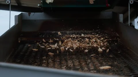 Industrial conveyor screen sorting wood chips as material falls onto moving 스톡 동영상 346317399