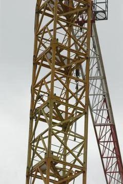 Industrial crane featuring red elements overlooking urban skyline scene Stock Photos