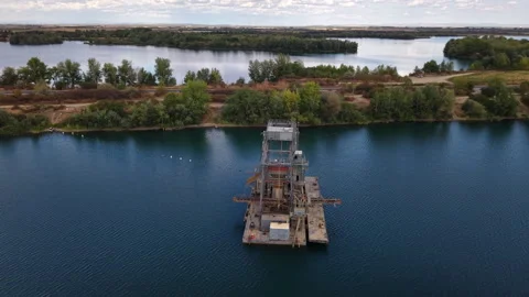 An industrial dredger barge actively working on a tranquil, deep blue lake with Stock Footage 345618740