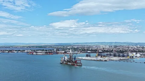 Industrial dredging vessel operates in a busy port area with machinery and Stock Footage 337905618