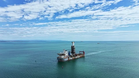 Industrial dredging vessel operates in open water under a clear sky with few Stock Footage 337905732