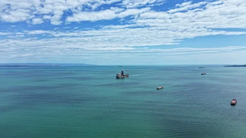 Industrial dredging vessel operates in open water under blue sky with scattered Stock Footage 339494840
