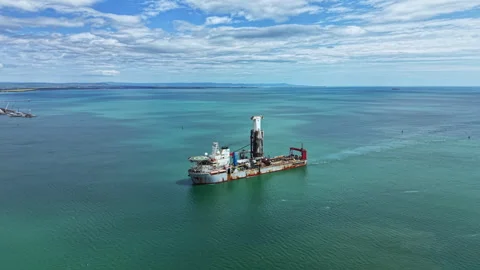 Industrial dredging vessel operates in open water near a coastal area with Stock Footage 340142767