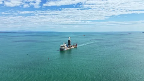 Industrial dredging vessel operates in open water near coastal area during clear Stock Footage 340147041