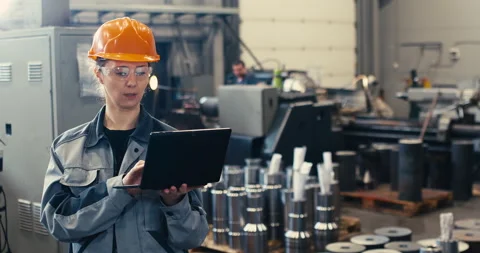 An industrial engineer in a hard hat in a protective jacket uses a laptop. He Stock Footage 171149985