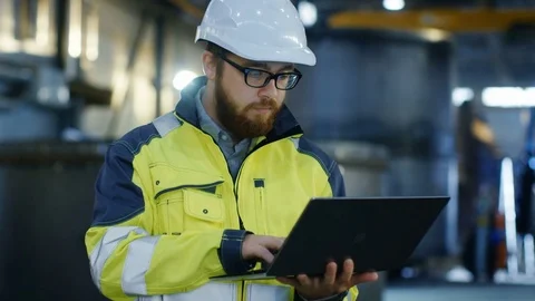 Industrial Engineer in Hard Hat Wearing Safety Jacket Uses Laptop.  Stock Footage 82382629