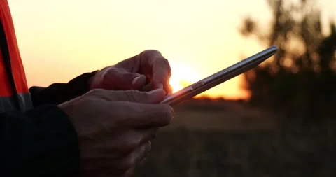 Industrial engineer uses tablet at sunset. He enters data, analyzes results Stock Footage 348431197