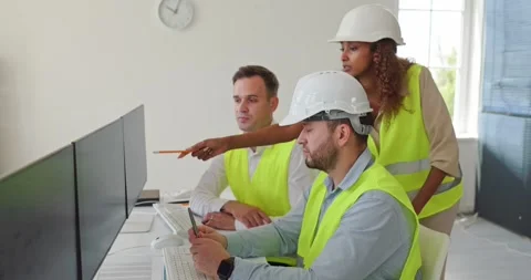 Industrial engineers analyzing data on monitors in safety vests and helmets Stock Footage 344917311