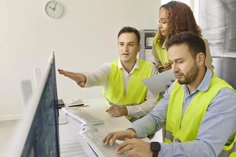 Industrial Engineers Overseeing Operations at Monitors in Secure Control Room Stock Photos
