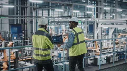 Industrial Engineers Talking Using Laptop at Car Factory Stock Footage 158934827