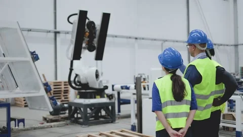 Industrial engineers working with arm robot inside AI robotic production factory Stock Footage 208663053