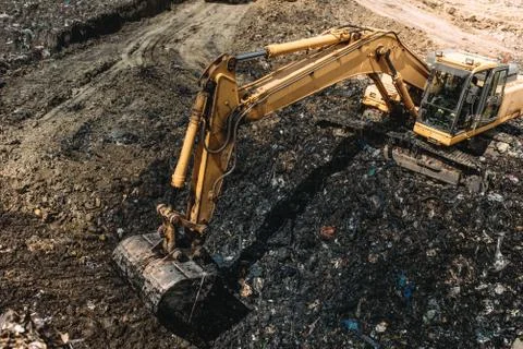Industrial excavators working on garbage dump. Heavy duty machinery at work Stock Photos