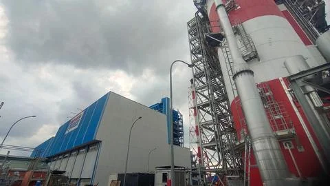 Industrial facility with large structures and cloudy skies. Stock Photos