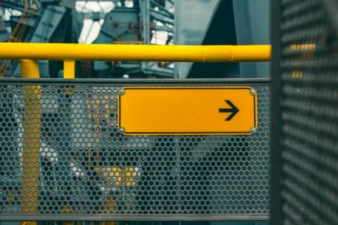 Industrial facility, yellow empty direction sign with black arrow Stock Photos