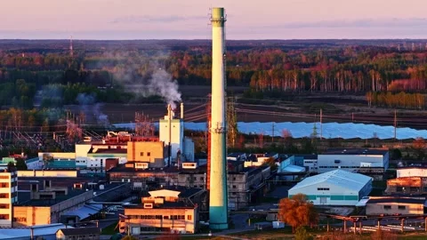 Industrial factory complex emitting smoke and pollution during a colorful sunset Stock Footage 337792108