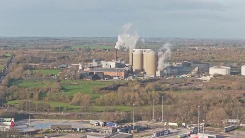 Industrial factory complex featuring silos and chimneys releasing steam and Stock Footage 321528045