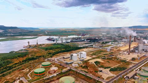 Industrial factory complex with storage tanks and smoking chimney near river Stock Footage 342327385