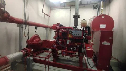 Industrial fire pump system with red piping and control panel. Stock Photos