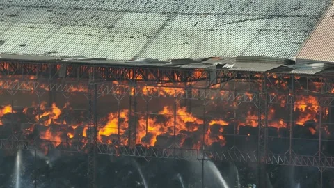 A industrial fire, showing extensive damage and ongoing flames. Stock Footage 274462133