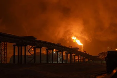 An industrial flare stack burns off excess gas with a large, bright orange fl Stock Photos