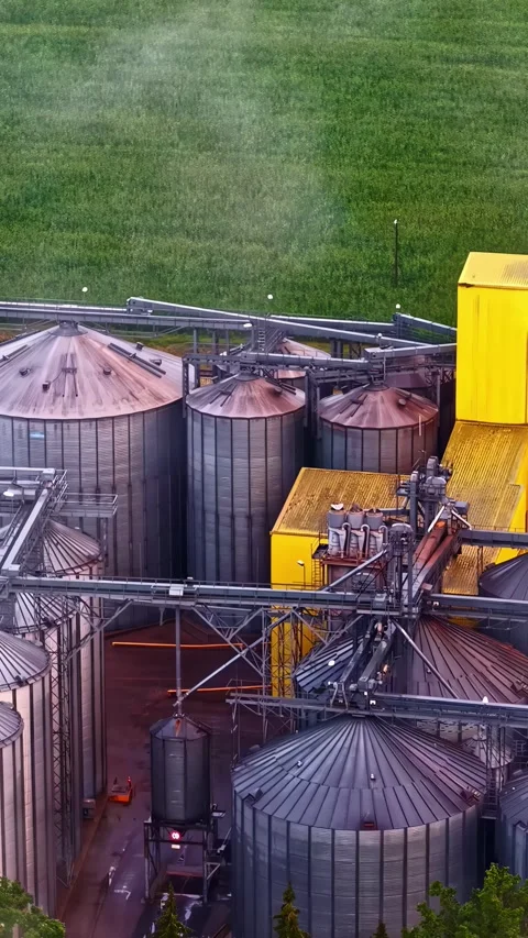 Industrial grain silos with storage tanks and conveyor systems beside expansive Stock Footage 341854573