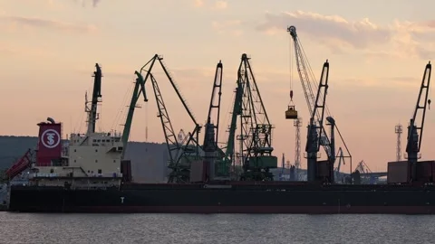 Industrial harbor cranes unloading cargo ship at sunset Stock Footage 340920711
