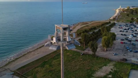 Industrial harbor lighting tower above seaside park and beach Stock Footage 343997066