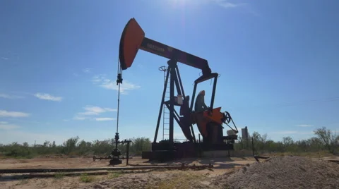 Industrial jack pump platform pumping crude oil in Texas desert Stock Footage 62221249