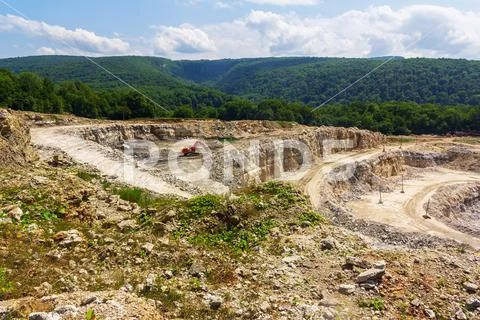 Industrial landscape with an excavator in quarry for the extraction of limest Stock Photos