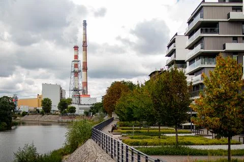 Industrial landscape features a river, modern buildings, and smokestacks under Foto stock