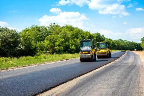 Industrial landscape with rollers that rolls a new asphalt in the roadway. Re Stock Photos