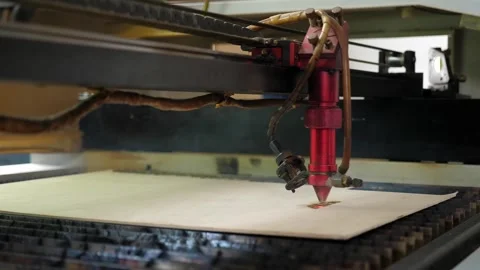 An industrial laser cuts a pattern on a sheet of plywood and moves close-up. Stock Footage 251123055