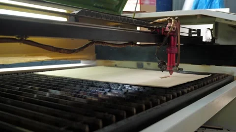 An industrial laser cuts a pattern on a sheet of plywood. A red laser beam. Stock Footage 288335272