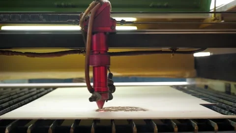 An industrial laser cuts a pattern on a sheet of plywood and moves close-up. Stock Footage 291516767