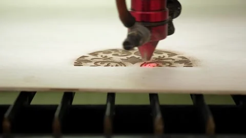 An industrial laser cuts a pattern on a sheet of plywood and moves close-up. Stock Footage 311152022