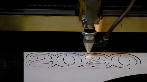 Industrial laser is cutting a pattern, numbers 2020, on a plywood sheet . Stock Footage 120711328