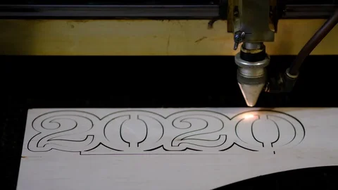 Industrial laser is cutting a pattern, numbers 2020, on a plywood sheet . Stock Footage 120712677
