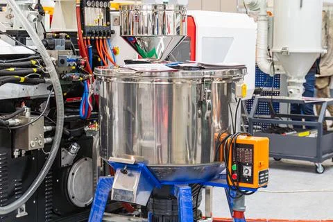 Industrial machine featuring reflective cylindrical container on blue stand.. Stock Photos