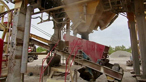 Industrial machinery setup with a red hopper, conveyor belt, and storage tanks Stock Footage 287248704