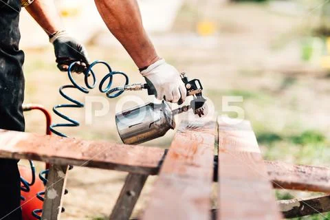 Industrial man painting brown timber, renovating exterior fence during new ho Stock Photos