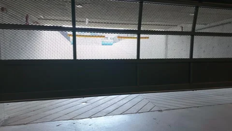 Industrial mesh security gate closing in underground parking garage structure Stock Footage 341960894