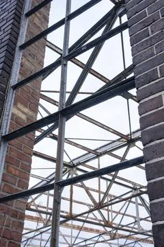Industrial metal framework within partial brick walls against a cloudy sky Stock Photos