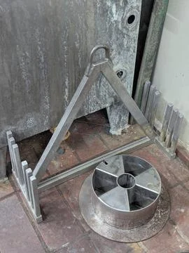 Industrial metal stand with triangular frame and ring handle against wall d.. Stock Photos