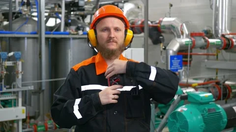 Industrial operator man with a beard in an orange helmet, headphones and glasses Stock Footage 171331306