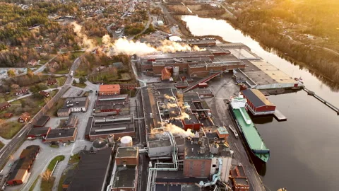 Industrial peper mill complex plant emitting smoke on the river bank at sunset Stock Footage 297067614